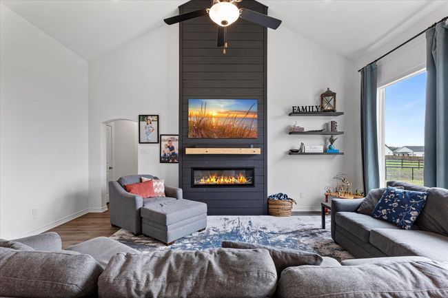 Living room with wood finished floors, a large fireplace, high vaulted ceiling, and a healthy amount of sunlight | Image 12