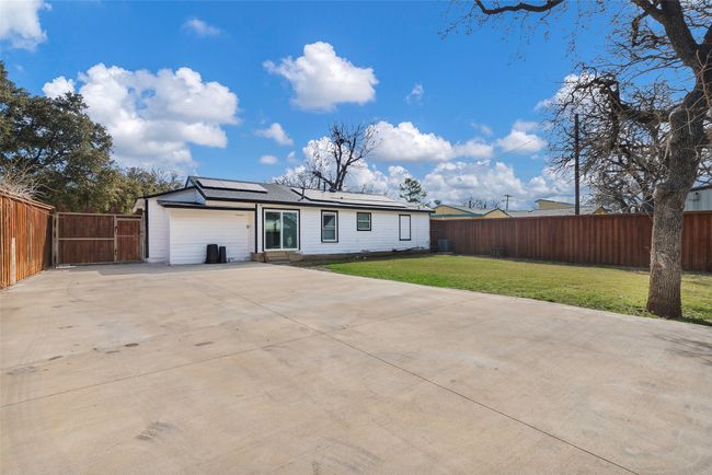 Back of house with solar panels, fenced in large private yard, and paved driveway | Image 15