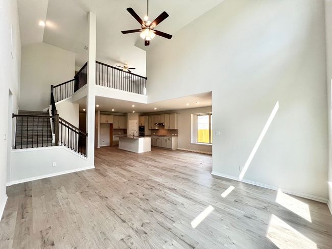 Unfurnished living room with stairs, light wood-type flooring, ceiling fan, a towering ceiling, and recessed lighting | Image 8