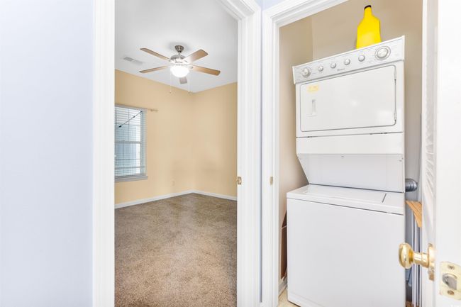 Laundry area featuring stacked washer / dryer, ceiling fan, carpet floors, and baseboards | Image 19