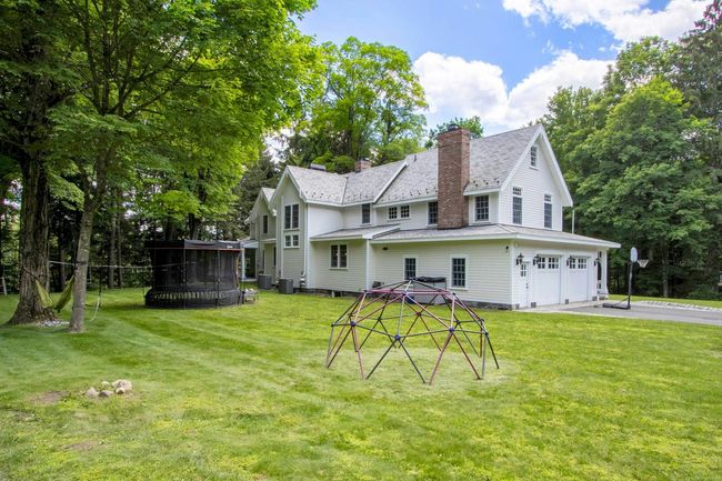 Back of house featuring a chimney, an attached garage, a lawn, central AC unit, and asphalt driveway | Image 35
