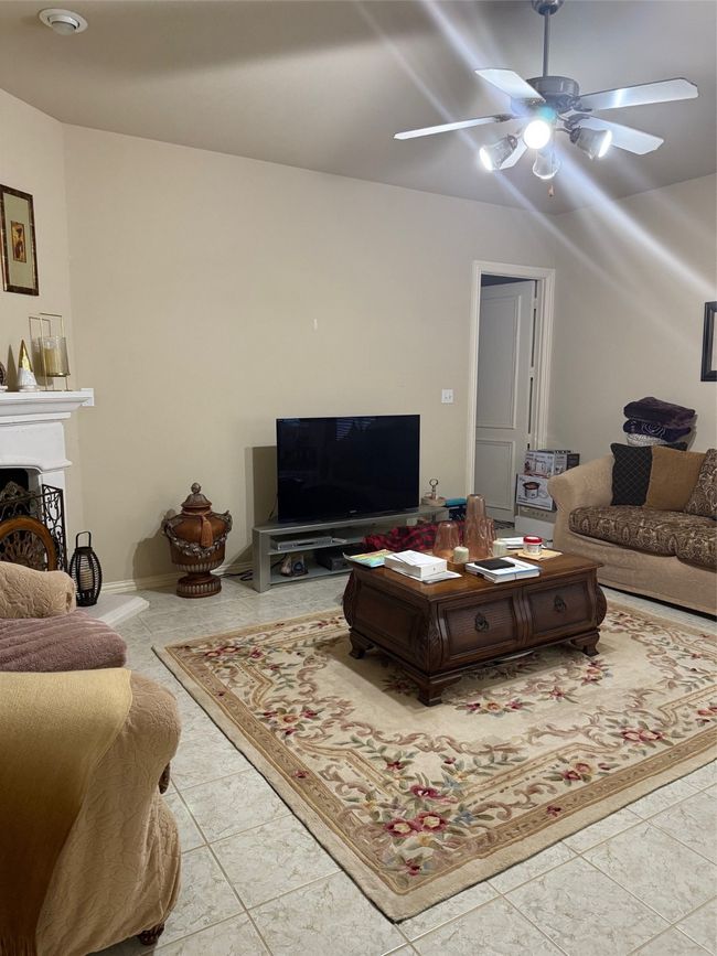 Living room with ceiling fan and a fireplace with raised hearth | Image 13