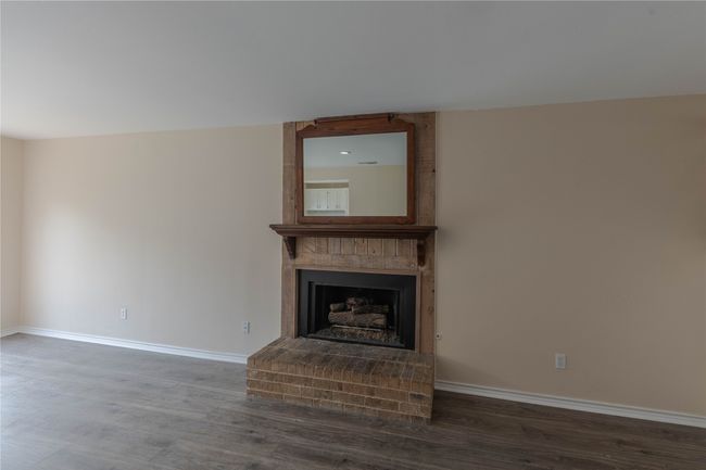Unfurnished living room featuring a brick fireplace, wood finished floors, and baseboards | Image 33