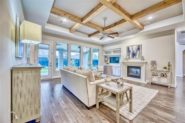 This inviting living room features a cozy fireplace, elegant wood beam ceiling, and large windows offering plenty of natural light. The open layout includes stylish hardwood floors and neutral decor, creating a warm, modern ambiance perfect for relaxation and entertaining. | Image 19