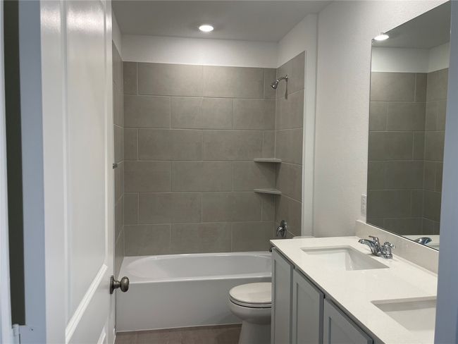 Bathroom featuring toilet, double vanity, and shower / bathtub combination | Image 15
