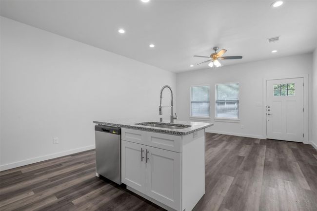 Kitchen with stainless steel dishwasher, ceiling fan, light stone counters, recessed lighting, and dark wood-type flooring | Image 4