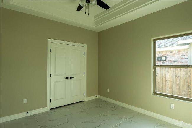 Unfurnished bedroom with marble finish floor, a closet, baseboards, and a tray ceiling | Image 34