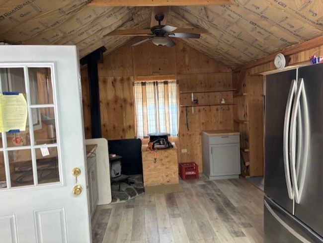 Kitchen featuring freestanding refrigerator, a wood stove, wood walls, ceiling fan, and Laminate style flooring | Image 11