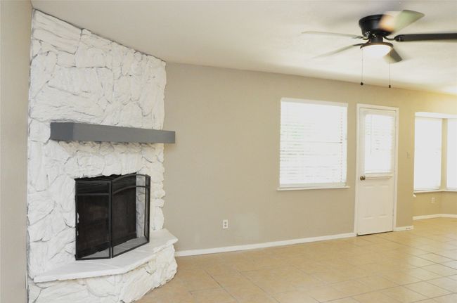Unfurnished living room with a fireplace, light tile patterned floors, a ceiling fan, and baseboards | Image 7