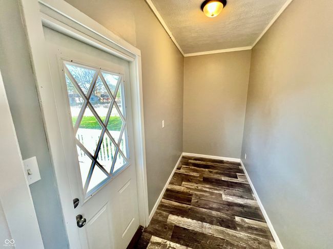 entryway with a textured ceiling, ornamental molding, baseboards, and dark wood-style floors | Image 22
