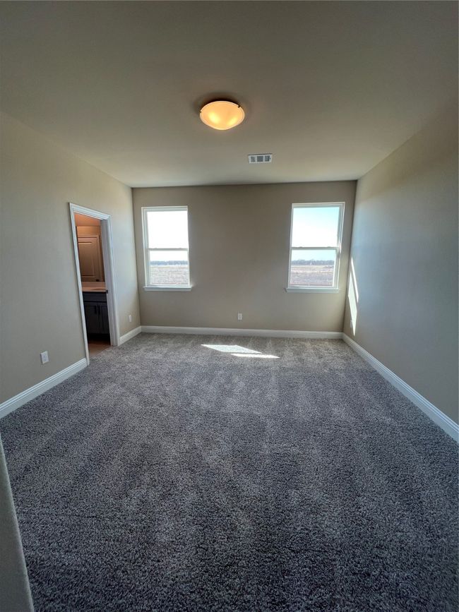 Unfurnished bedroom with dark colored carpet, multiple windows, visible vents, and baseboards | Image 8