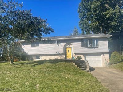 View of front of home featuring an outdoor structure, a front lawn, and a garage | Image 1