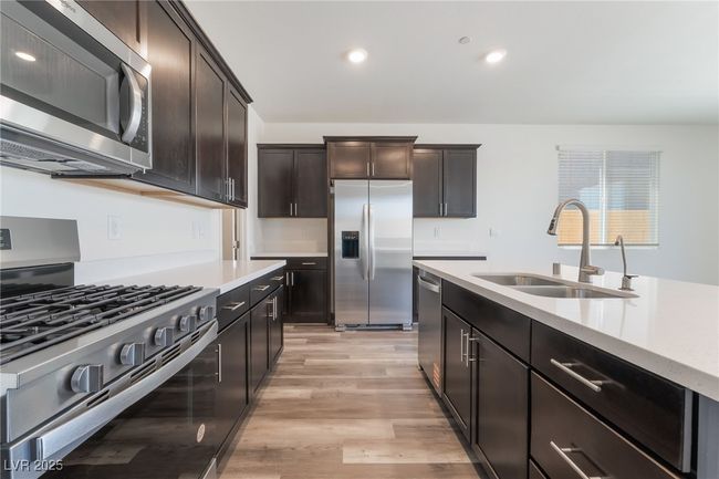 Kitchen with appliances with stainless steel finishes, light countertops, light wood-type flooring, recessed lighting, and dark brown cabinets | Image 13