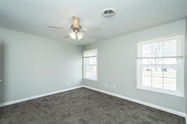 Spare room with dark colored carpet, visible vents, baseboards, and a ceiling fan | Image 23
