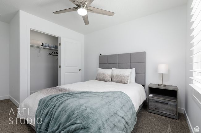 Bedroom with dark carpet, ceiling fan, a closet, and baseboards | Image 27