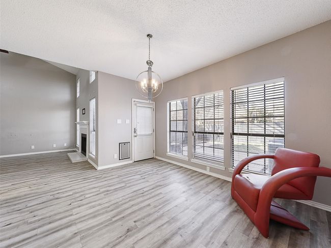 Living area featuring an inviting chandelier, baseboards, light wood-type flooring, and a textured ceiling | Image 9