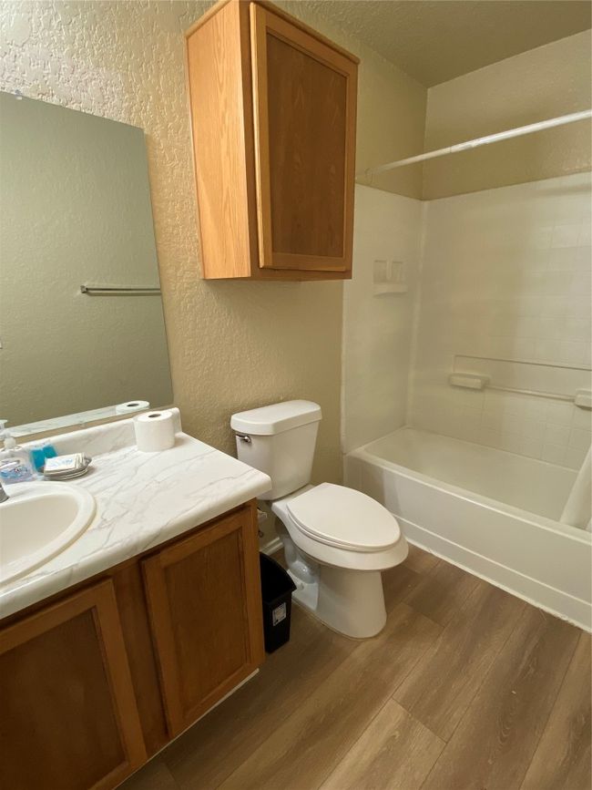Full bath with a textured wall, wood finished floors, vanity, tub / shower combination, and toilet | Image 14