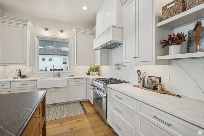 Kitchen featuring open shelves, white cabinetry, high end range, and a sink | Image 16