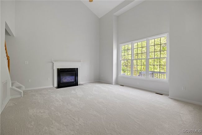 Unfurnished living room with visible vents, high vaulted ceiling, a fireplace, and carpet, and 2nd staircase to second floor | Image 20