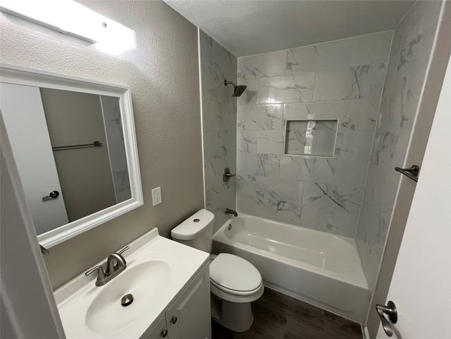 Bathroom with vanity, toilet, wood finished floors, shower / tub combination, and a textured wall | Image 9