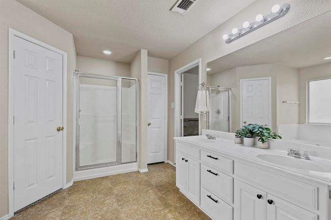 Bathroom with visible vents, a sink, a shower stall, and double vanity | Image 24
