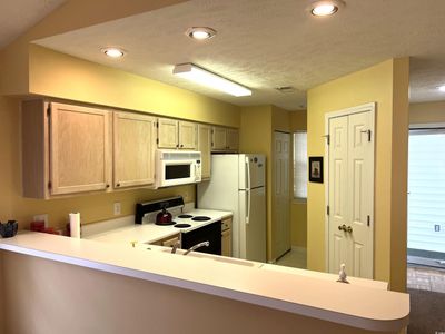 Kitchen with light brown cabinets, a textured ceiling, kitchen peninsula, and white appliances | Image 3