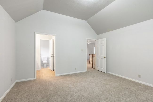 Unfurnished bedroom with vaulted ceiling, light carpet, baseboards, and ensuite bath | Image 39