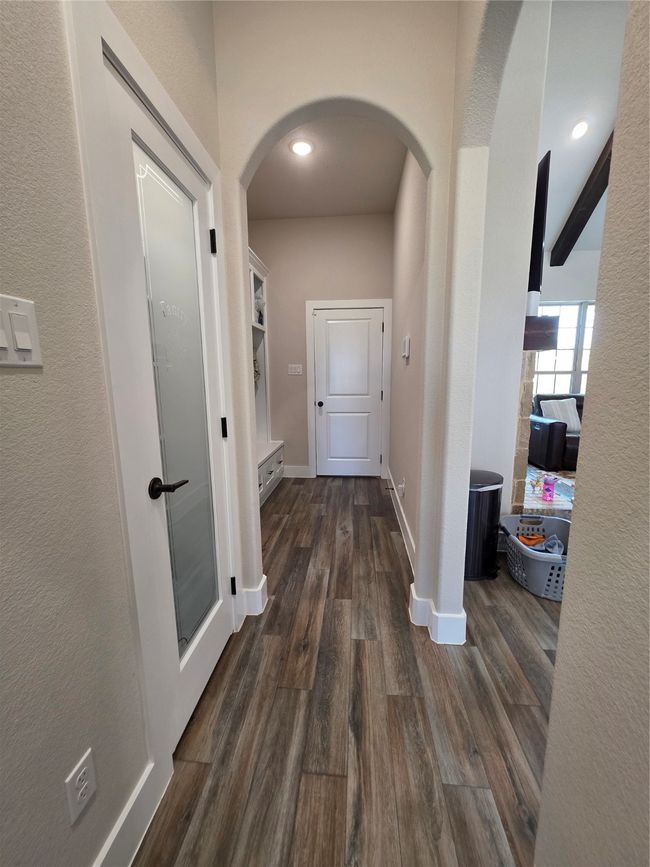 Corridor with arched walkways, dark wood finished floors, recessed lighting, and a textured wall | Image 16
