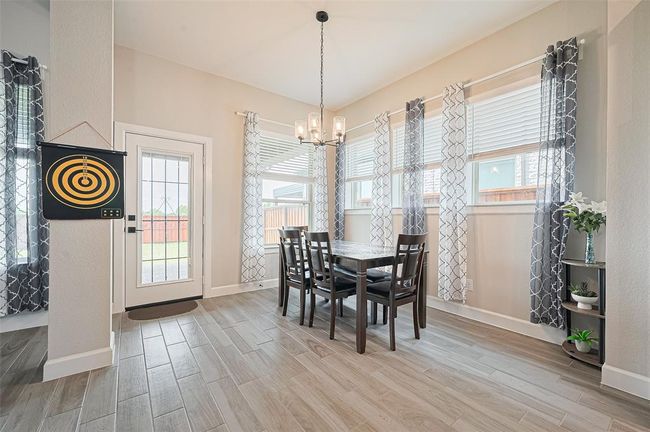 Charming dining area surrounded by windows, offering a bright and cozy space for family meals with views of the backyard. | Image 10