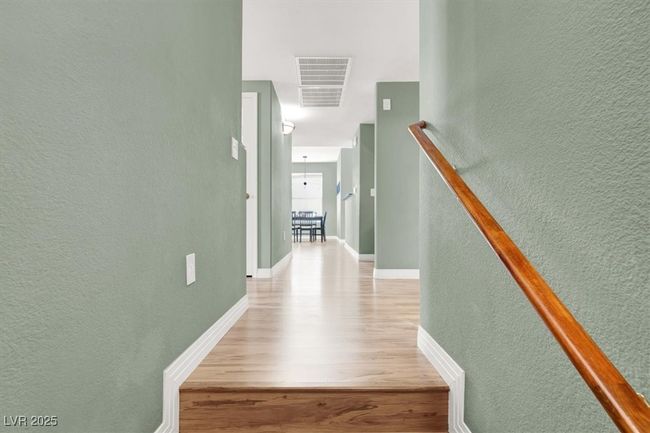 Hall with visible vents, a textured wall, wood like finished floors, and baseboards | Image 4