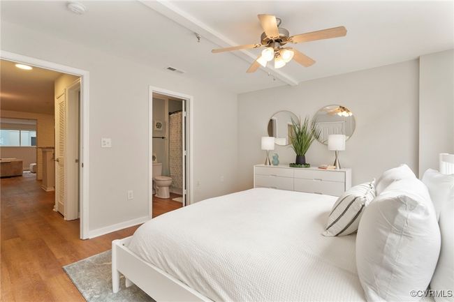 Bedroom featuring light wood-type flooring, ensuite bathroom, beam ceiling, and ceiling fan | Image 11