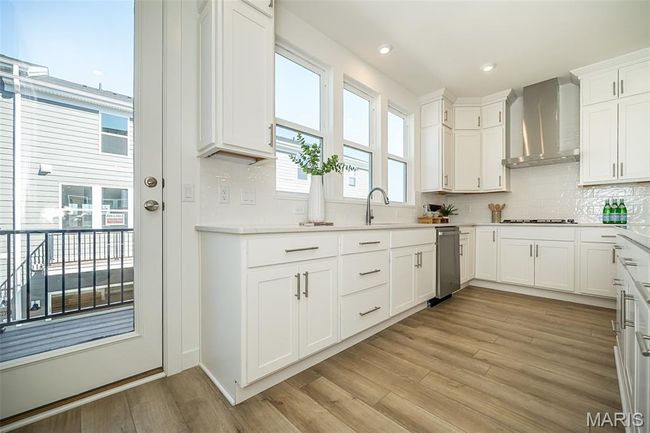 Kitchen featuring backsplash, white cabinetry, light wood-style floors, light countertops, and recessed lighting | Image 7