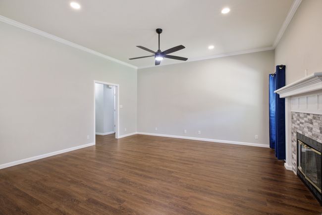 Unfurnished living room featuring a fireplace, ornamental molding, a ceiling fan, dark wood-style flooring, and recessed lighting | Image 28