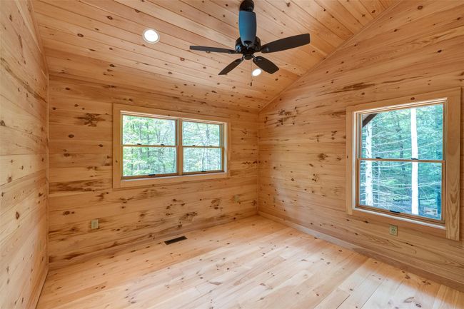 Unfurnished room featuring lofted ceiling, light wood-style floors, a ceiling fan, wooden walls, and wooden ceiling | Image 29