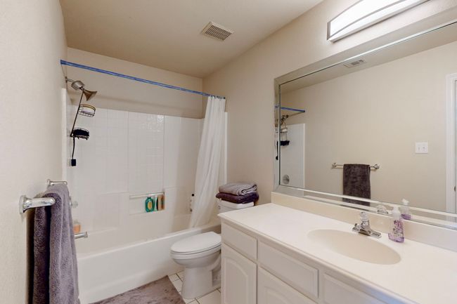 Bathroom featuring vanity, shower / bathtub combination with curtain, toilet, tile patterned flooring, and visible vents | Image 27