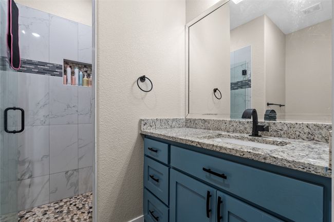 Bathroom featuring a shower stall, vanity, and a textured wall | Image 32