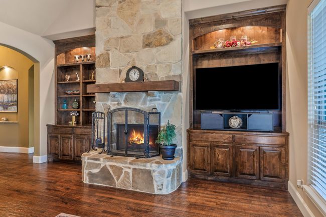 Living room featuring dark wood-style flooring, arched walkways, a fireplace, and built in features | Image 11