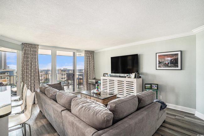 Living room featuring a textured ceiling, crown molding, dark wood finished floors, and a city view | Image 6