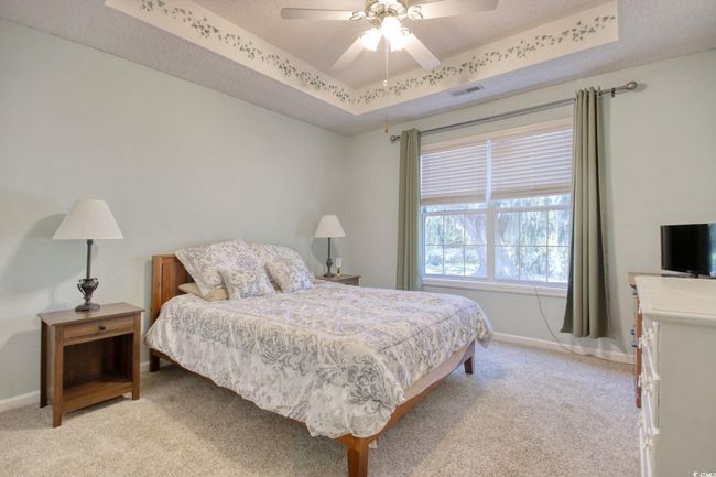 Bedroom with light carpet, a raised ceiling, and a ceiling fan | Image 23