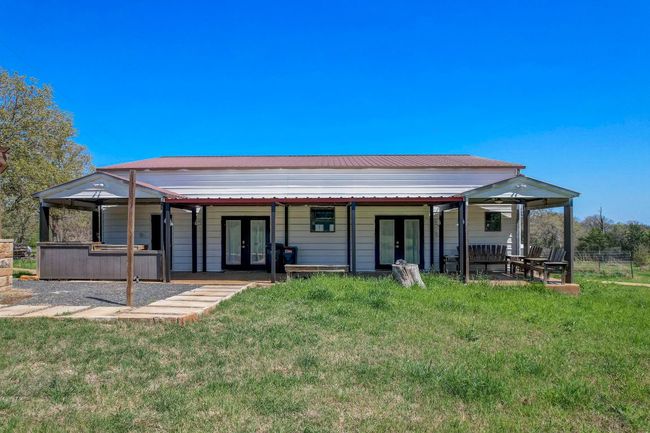 Rear view of property featuring french doors, a patio area, a yard, and metal roof | Image 10