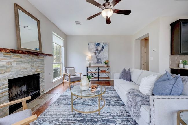 Living room with a fireplace, light wood finished floors, and a ceiling fan | Image 13