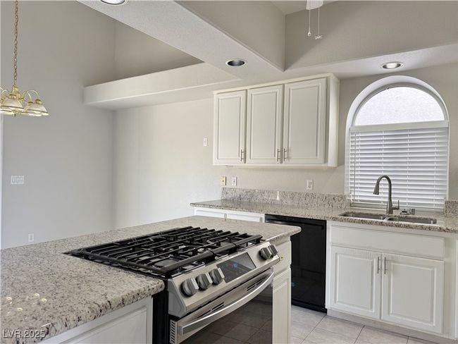 Kitchen with stainless steel range with gas stovetop, white cabinets, dishwasher, and a sink | Image 11