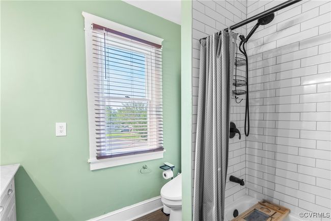 Bathroom with toilet, vanity, shower / tub combo with curtain, and baseboards | Image 31