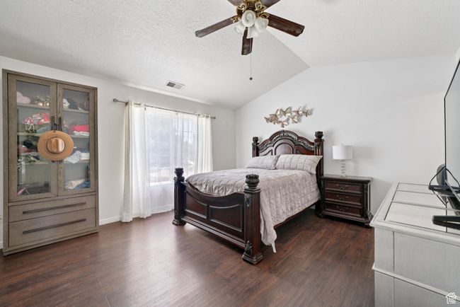 Bedroom featuring vaulted ceiling, dark wood-style floors, a ceiling fan, and a textured ceiling | Image 15
