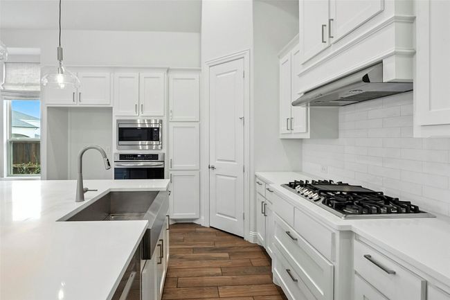 Kitchen featuring white cabinetry, light countertops, tile floors, and stainless steel appliances | Image 6