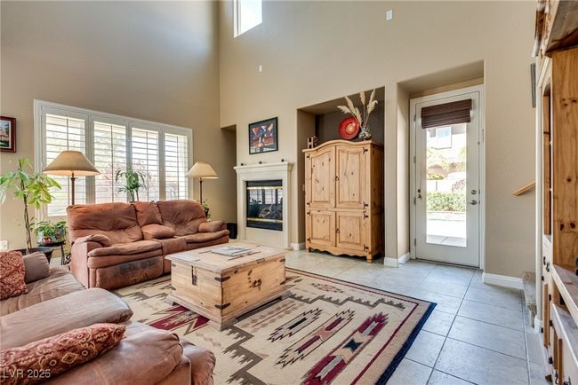 Living room with baseboards, a high ceiling, a glass covered fireplace, and light tile patterned floors | Image 29