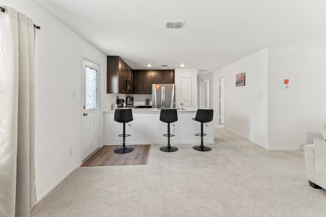 Kitchen with freestanding refrigerator, dark brown cabinetry, light colored carpet, a breakfast bar area, and light countertops | Image 6