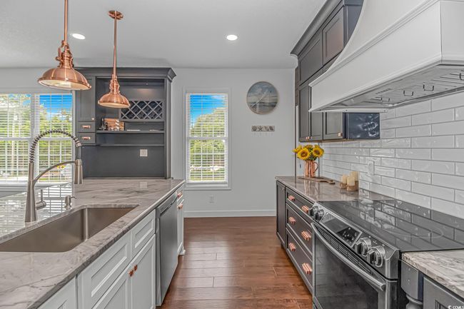 Kitchen featuring stainless steel appliances, custom exhaust hood, a sink, tasteful backsplash, and baseboards | Image 14