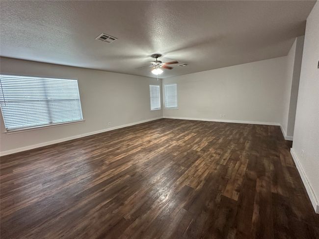 Unfurnished room featuring a ceiling fan, dark wood-style flooring, and a textured ceiling | Image 4