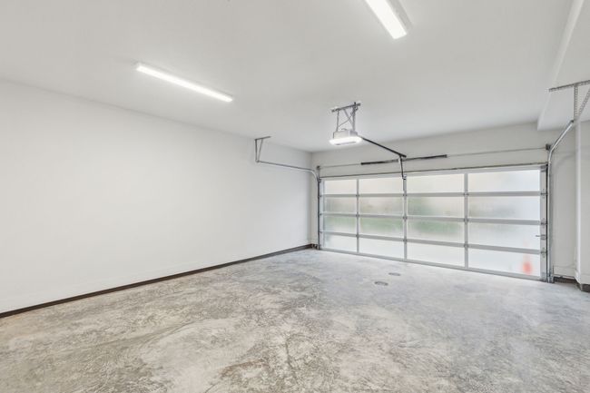 Garage featuring a garage door opener and baseboards | Image 29